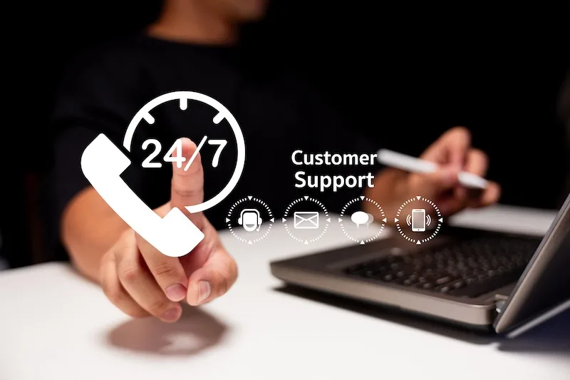 A Person Gestures Towards A 24/7 Customer Support Graphic While Using A Laptop, Symbolizing Accessibility And Assistance. A Person Gestures Towards A 24/7 Customer Support Graphic While Using A Laptop, Symbolizing Accessibility And Assistance.