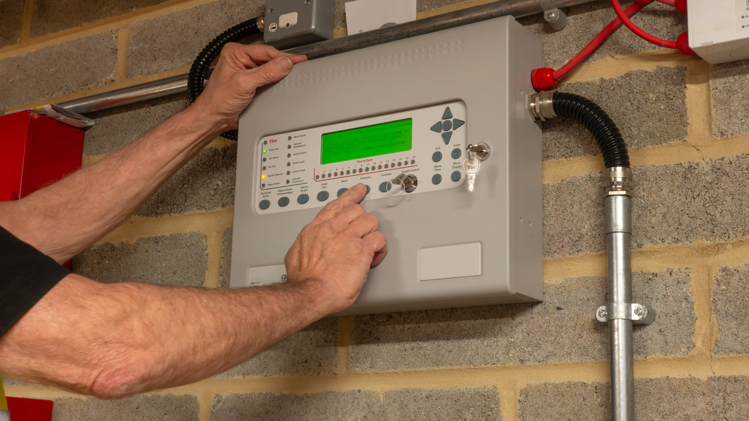 Fire Alarm Engineer Investigating A Fault On A Fire Protection System During Planned Maintenance, Ensuring The Safe And Reliable Operation Of Industrial Fire Suppression Equipment. Fire Alarm Engineer Investigating A Fault On A Fire Protection System During Planned Maintenance, Ensuring The Safe And Reliable Operation Of Industrial Fire Suppression Equipment.
